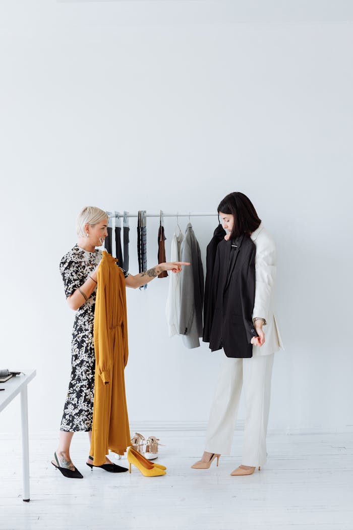 Two women discussing clothing choices in a minimalist boutique setting.